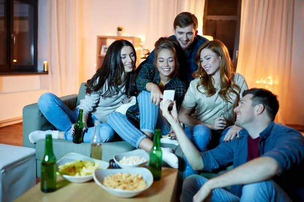 Amigos felices con teléfono inteligente en la fiesta en casa —  Fotos de Stock