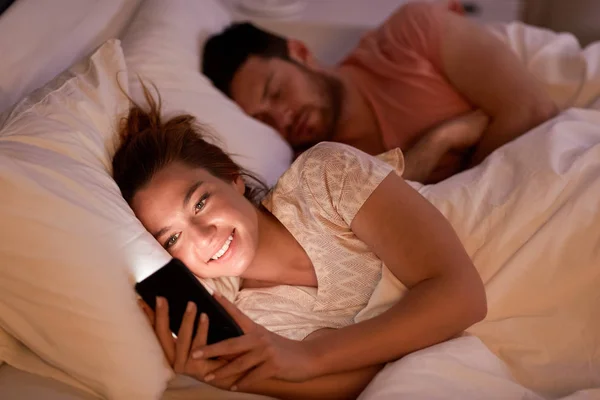 Woman using smartphone while boyfriend is sleeping — Stock Photo, Image