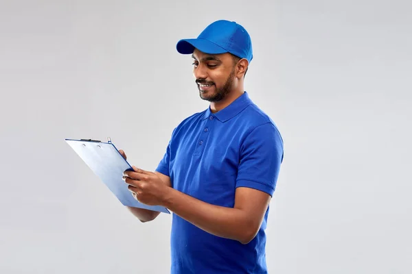 Homem de entrega indiana feliz com prancheta em azul — Fotografia de Stock