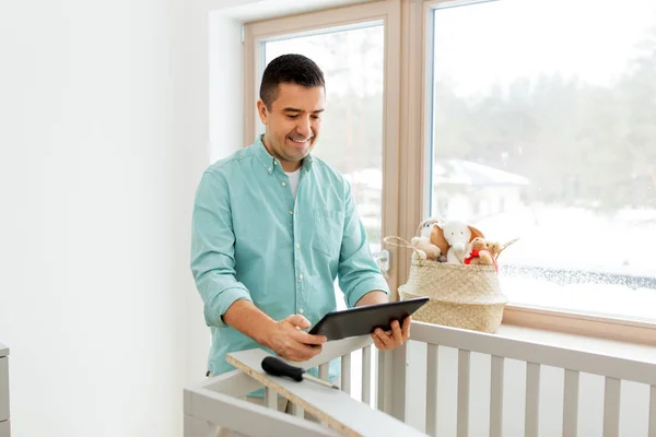 Vader met tablet pc monteren babybed thuis — Stockfoto