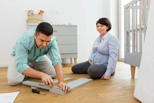 Familienpaar baut Babybett zu Hause zusammen — Stockfoto