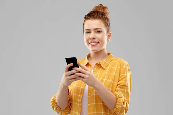 Usměvavý červený vlasy dospívající dívka pomocí smartphonu — Stock fotografie