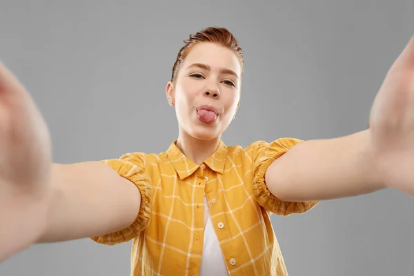 Rödhåriga tonårs flicka tar selfie med tungan — Stockfoto