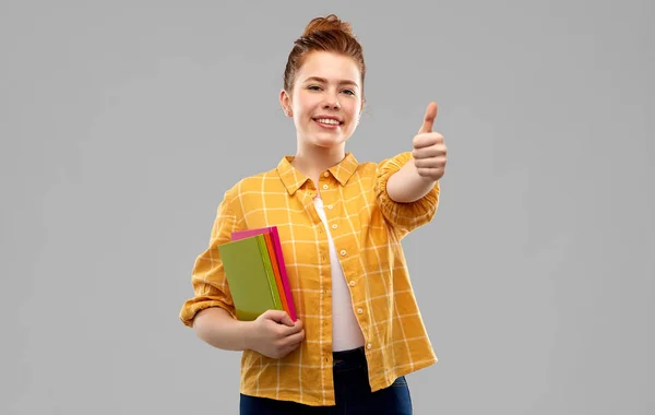 Adolescente menina estudante com livros mostrando polegares para cima — Fotografia de Stock