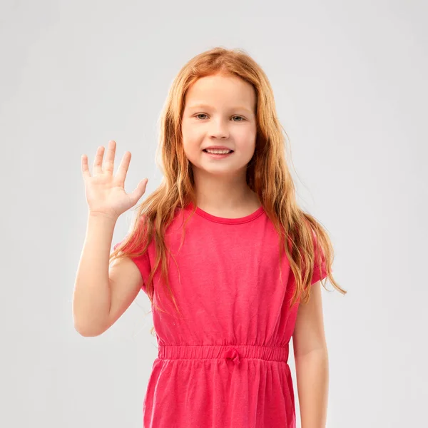 Sorrindo menina de cabelos vermelhos no vestido rosa acenando mão — Fotografia de Stock