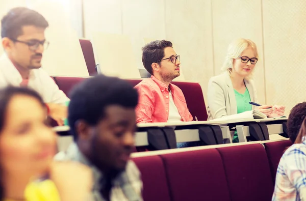 Grupo de estudiantes con cuadernos en la sala de conferencias — Foto de Stock