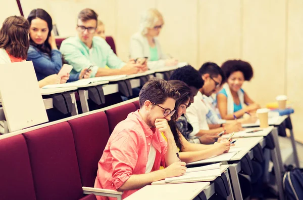Group of students with notebooks in lecture hall — Stock Photo, Image