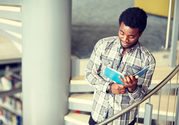 Africano estudiante chico o hombre lectura libro en biblioteca —  Fotos de Stock