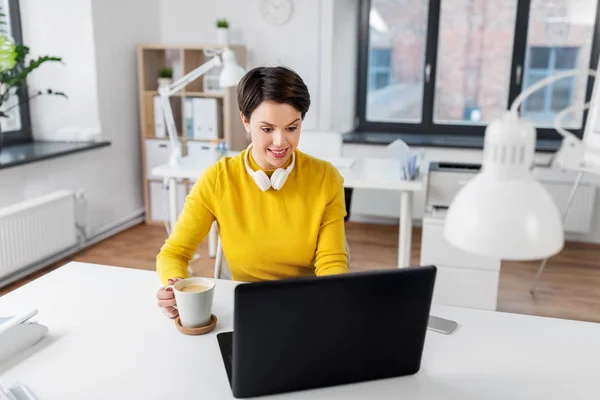 Деловая женщина с ноутбуком пьет кофе в офисе — стоковое фото