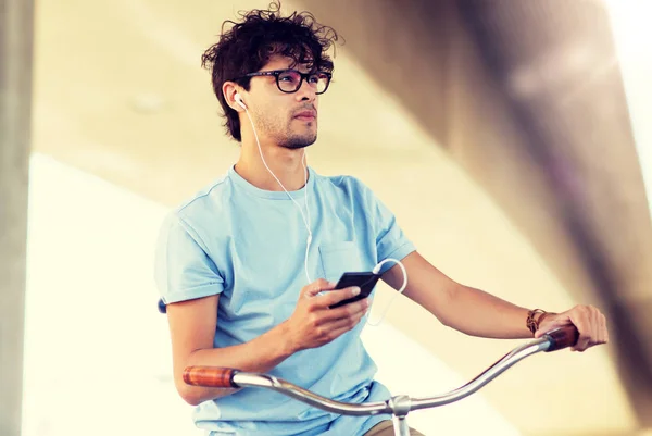 Homem com smartphone e fones de ouvido na bicicleta — Fotografia de Stock