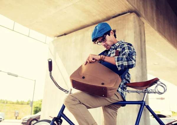 Hipster man med cykel ser något i väska — Stockfoto