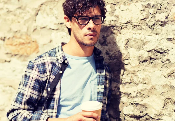 Man in eyeglasses drinking coffee over street wall — Stock Photo, Image