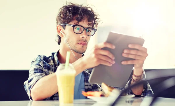 Uomo con tablet pc e auricolari seduto al caffè — Foto Stock