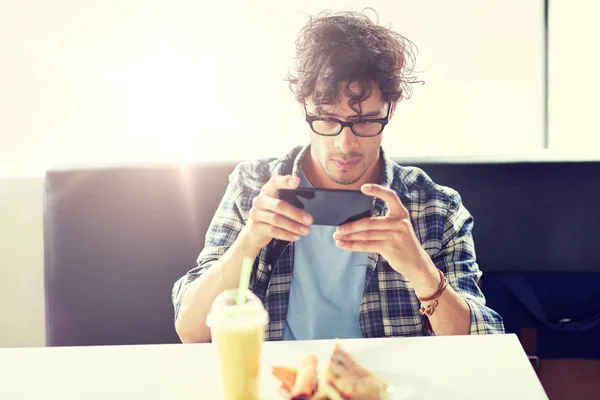 Mannen med smartphone fotograferar mat på café — Stockfoto