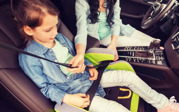 Feliz mujer sujeción niño con cinturón de seguridad en el coche — Foto de Stock