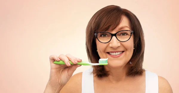 Senior vrouw met tandenborstel poetsen haar tanden — Stockfoto