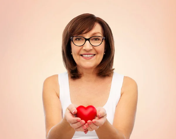 Ritratto di donna anziana sorridente che tiene il cuore rosso — Foto Stock