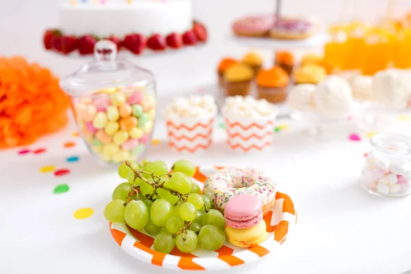 Uvas, macarrones y rosquillas en la mesa de fiesta — Foto de Stock