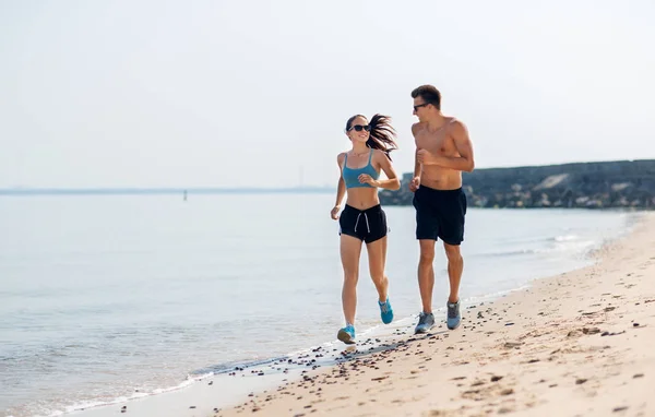 Koppel in sport kleding lopen langs op het strand — Stockfoto