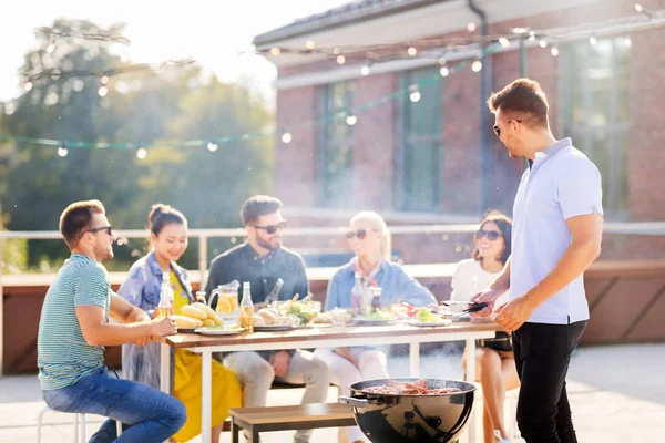 man grilling meat on bbq at rooftop party