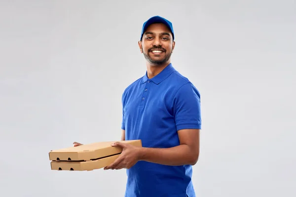 Glücklicher indischer Lieferant mit Pizzakartons in blau — Stockfoto