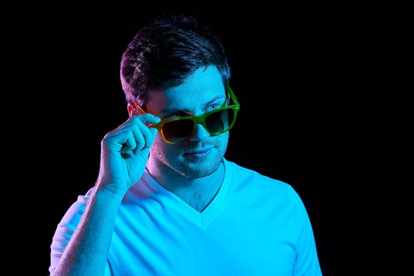 Человек в солнечных очках над ультрафиолетовым неоновым светом — стоковое фото