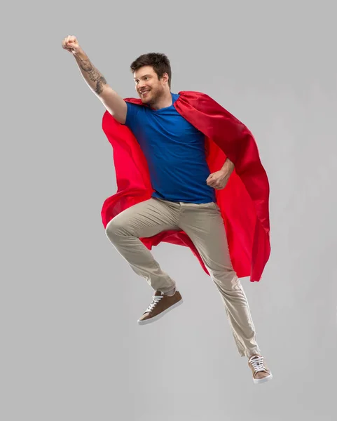 Hombre en capa de superhéroe rojo volando en el aire —  Fotos de Stock