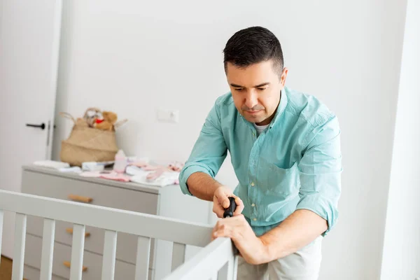 Gelukkig vader met schroevendraaier montage babybed — Stockfoto