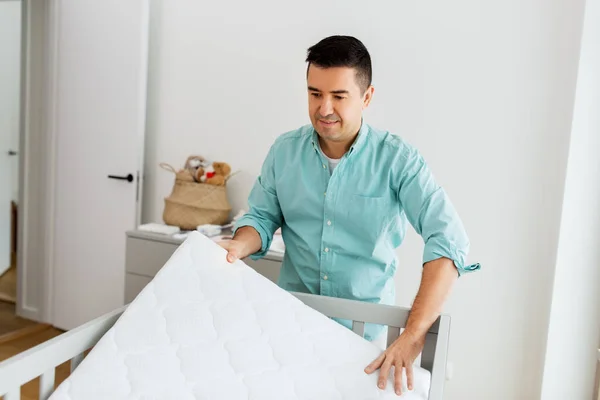 Père arrangeant lit bébé avec matelas à la maison — Photo