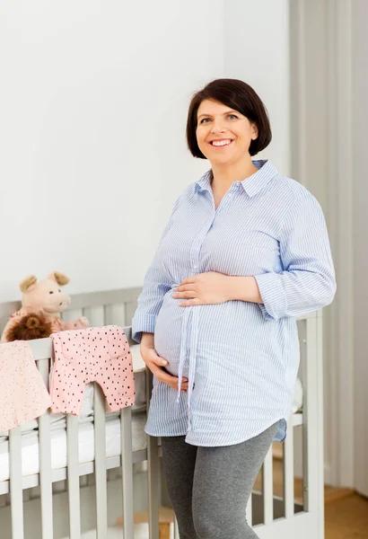 Gelukkig zwangere vrouw naast babybed thuis — Stockfoto