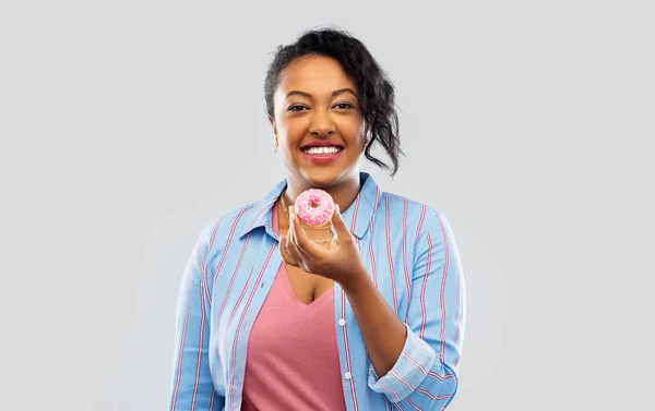 Heureux afro-américain femme manger beignet rose — Photo