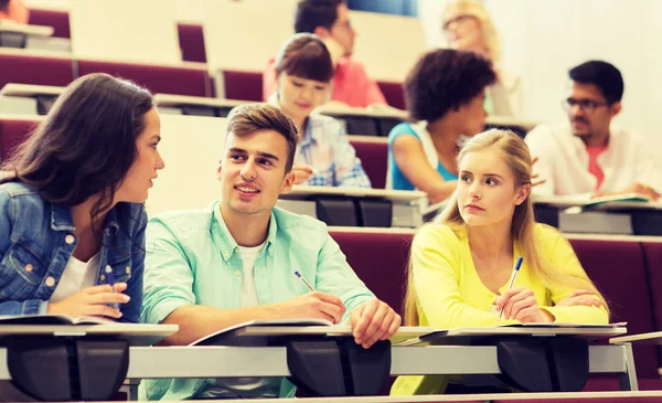 Grupp studenter med anteckningsböcker i föreläsningssalen — Stockfoto