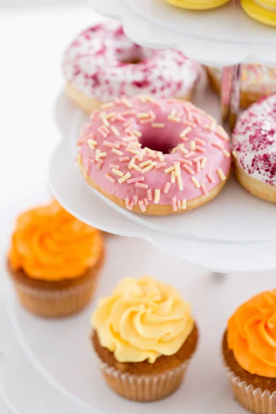 Primer plano de rosquillas vidriadas y cupcakes en stand — Foto de Stock