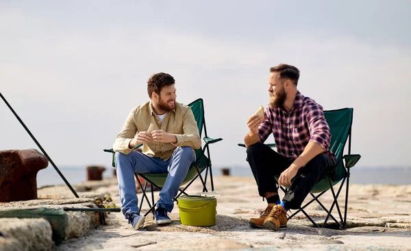 Happy friends fishing and eating sandwiches — Stock Photo, Image