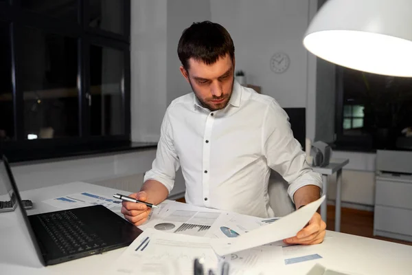 Homme d'affaires avec papiers et ordinateur portable au bureau de nuit — Photo