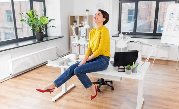 Happy podnikatelka sedí na stole v kanceláři — Stock fotografie