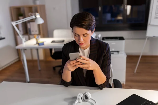 Business woman using smartphone at night office — стоковое фото