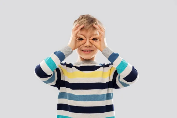 Menino no pulôver olhando através de óculos de dedo — Fotografia de Stock