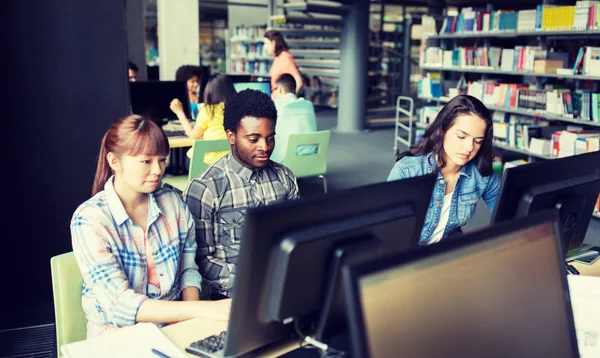 Mezinárodní studenti s počítači v knihovně — Stock fotografie