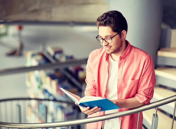 Student chłopiec lub młody człowiek czytania książki w bibliotece — Zdjęcie stockowe