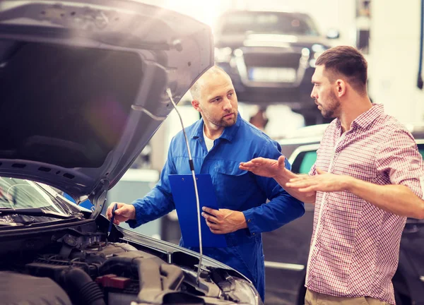 Automechaniker mit Klemmbrett und Mann im Autohaus — Stockfoto