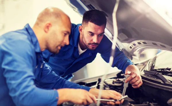 Hombres mecánicos con llave inglesa reparación de coches en el taller — Foto de Stock