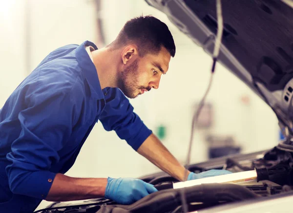 Mecânico homem com lâmpada reparando carro na oficina — Fotografia de Stock