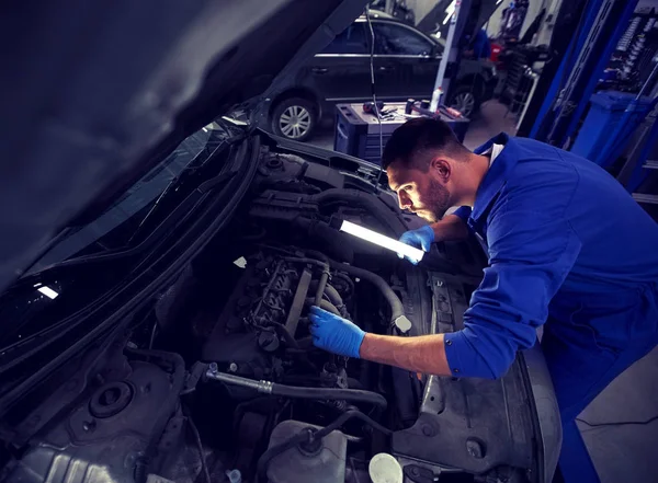 Mecánico hombre con lámpara de reparación de coches en el taller — Foto de Stock