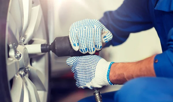 Mecânico com chave de fenda trocando pneu do carro — Fotografia de Stock