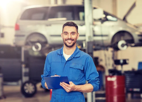 Glücklicher Mechaniker mit Klemmbrett in Autowerkstatt — Stockfoto