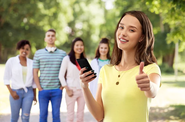 Dospívající dívka s smartphone ukazuje palec — Stock fotografie