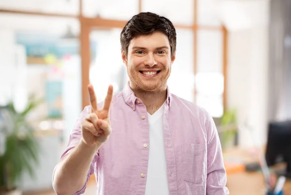 Mann zeigt zwei Finger oder Frieden über Bürozimmer — Stockfoto