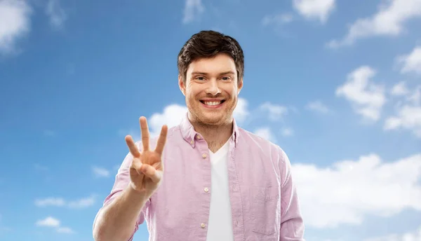 Joven mostrando tres dedos sobre el cielo — Foto de Stock