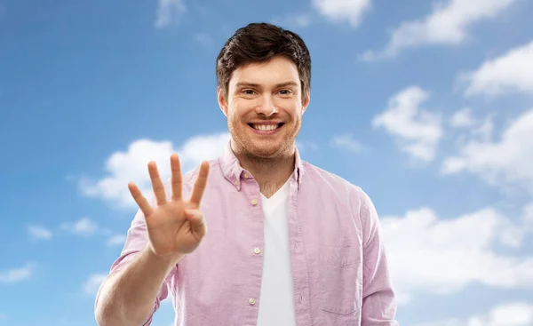 Young man showing four fingers over sky — Stock Photo, Image